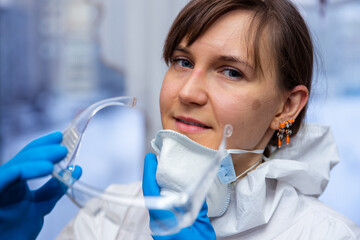 Female doctor takes off her protective mask after hard day at work. Concept of combating coronavirus.