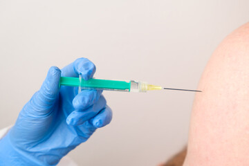 A doctor or nurse in rubber gloves gives a shot or injection. Vaccination against coronavirus, SARS-Cov-2.