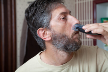 Obraz premium Haircut beard with gray hair trimmer close-up