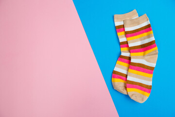 multicolored jersey socks on a pastel pink and blue background. view from above