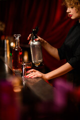 view of bar counter with bar equipment behind which woman bartender prepares cocktail