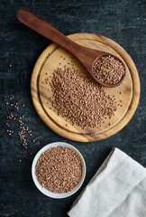 Buckwheat on cutting board, in wooden spoon and ceramic bowl, gluten free ancient grain for healthy eating, flat lay