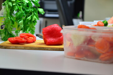 Closeup of hands of chef cook cutting red bell pepper vegetables on wooden table puts in a box to freeze
