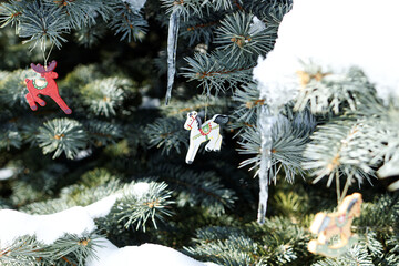 Vintage Christmas tree decoration. Retro toys and icicles on snow-covered tree branches outside in garden.