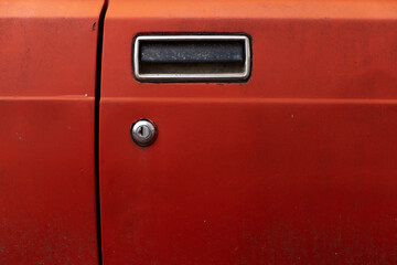 Vintage chrome door handle on red car rough aged surface on a Russian or Eastern European classic car in Sofia, Bulgaria