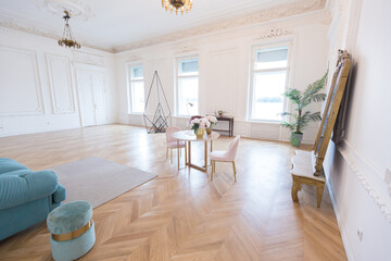 chic spacious light room in an old mansion in the classical style of the 19th century with a high ceiling decorated with stucco on white walls
