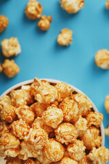 Caramel popcorn in a cup on a blue background, top view.