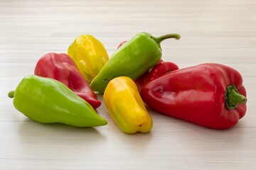 Colorful bell peppers (Capsicum annuum) vegetables. Yellow green red paprika on light wooden background. Bio food for preparing healthy nourishment. Fresh organic products in bright different colors.