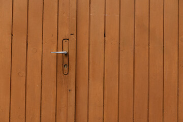 Orange painted wooden door with metal handle garage antique balkan aged with rusted metal bars in...
