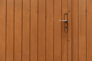 Orange painted wooden door with metal handle garage antique balkan aged with rusted metal bars in Sofia, Bulgaria, Eastern Europe