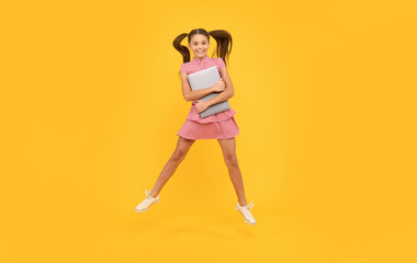 cheerful teen girl jump hold computer for study online, school