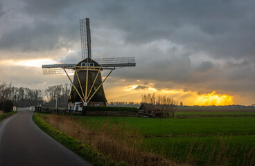 Fototapeta na wymiar Traditional dutch windmill during dramatic sunset in Amsterdam south