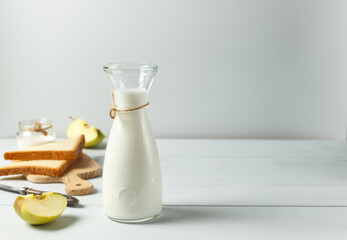 Fermented drink, kefir, natural yogurt in a glass carafe. On a light wooden background, with space