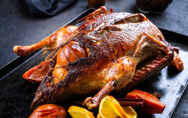 Traditionelle gebratene gefüllte Weihnachts Gans mit Quitten und Orangen Scheiben serviert als close-up auf einem rustikalen Metall Tablett