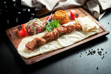 Chicken kebab cooked on the grill with lavash, bulgur and grilled vegetables on a wooden board. Turkish kebab. Close up ,selective focus