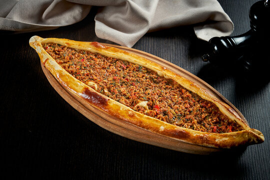 Turkish pide with minced lamb, tomatoes, bell pepper on a black background