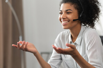 Portrait of excited laughing African American gamer girl or a customer service agent in wireless...