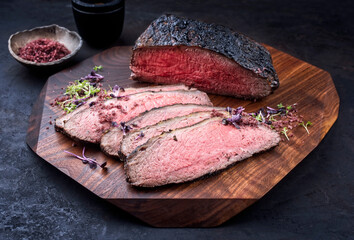 Modern style traditional Commonwealth Sunday roast with sliced cold cuts roast beef with herbs and salt served as close-up on a wooden design board