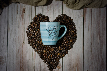 Coffee cup on heart shaped coffee beans.  Selective focus.