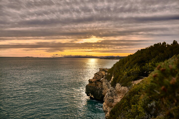 sunset on the coast with cliffs full of vegetation