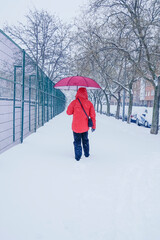 Person walking through the snow. Person with red clothes and umbrella