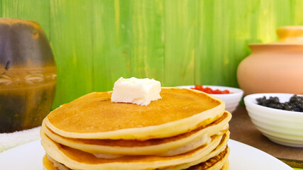 pancakes on a white plate. on the pancakes - a piece of butter. black sturgeon and red salmon...