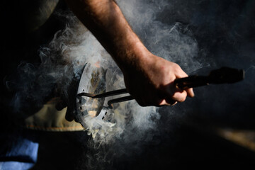Farrier hot shoeing a horse - adjusting a hot horseshoe to the hoof