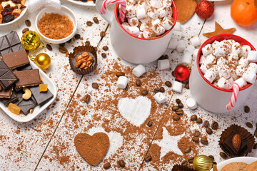 sweet food top view background for merry christmas or new year holiday decoration - chocolate candies, tangerines, cookies, marshmallow and cocoa latte on white wood