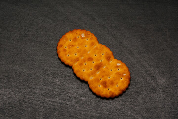 Beautiful, childish cracker on a black background. A golden cracker lies with crumbs on a black table.
