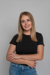 Attractive blonde girl wearing black shirt and jeans against grey background in studio