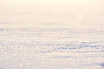 Winter background of white snow sparkling in the sun. The foreground and background are blurred. Photo with bokeh.