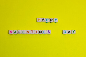 the text of "happy valentine's day" made of cubes, on a yellow background