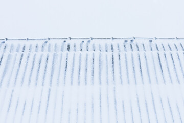 The roof of the house is covered with snow after a snowstorm. Winter season and a lot of snow fell.