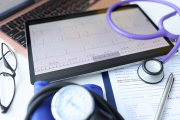 Digital tablet with electrocardiogram lying on doctors desk closeup - obrazy, fototapety, plakaty