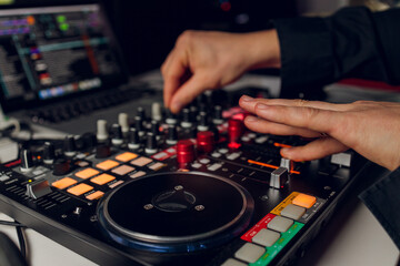 DJ's hand over the laptop and mixing console controlling the sound settings.
