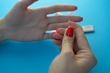 finger puncture to diagnose coronavirus. girl with red manicure makes herself an analysis on her own. finger puncture for blood sampling. girl holding a lancet and pricks her finger