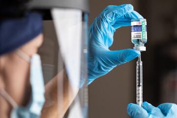 Doctor or Nurse Wearing Surgical Gloves Holding Vaccine Vial and Medical Syringe