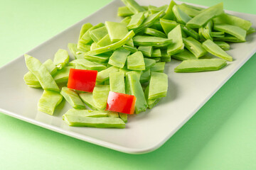 Green beans and chunks of bell pepper in a green tone plate