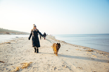 Woman walking dog on the beach in winter