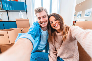 Husband and wife take a selfie moving in new home - Young couple just moved into new apartment - People and relocation concept.