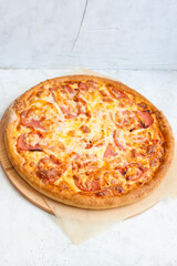 Pizza with mozzarella cheese, ham, tomatoes and sauce on plain grey background