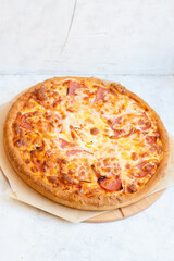 Pizza with mozzarella cheese, ham, tomatoes and sauce on plain grey background