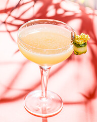 yellow tropical cocktail on a background of foliage and shadows from sunlight
