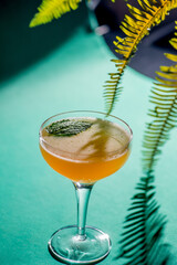 yellow tropical cocktail on a background of foliage, shadows from the sun. Green background