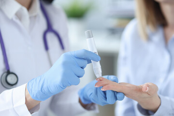 Nurse drawing blood from patient with lancet closeup