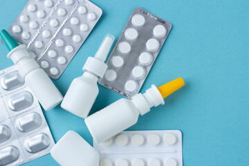 White pills set with nasal spray flat lay for blogger medicine content with copy space on blue...