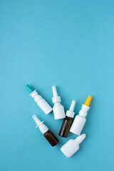 Bottles of nasal spray standing in line on blue background, medicine flat lay, treatment for colds, medical banner