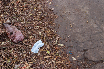 Dirty used disposable medical face mask dumped as garbage on asphalt street. Waste during COVID-19. Pollution due coronavirus pandemic