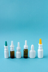 Bottles of nasal spray standing in line on blue background, medicine flat lay, treatment for colds, medical banner