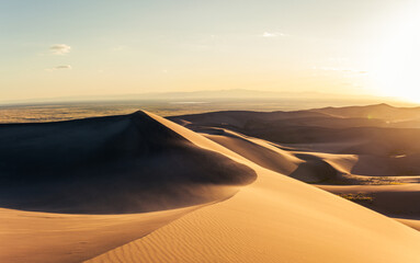 Fototapeta na wymiar Panorama of windy sandy dunes at golden sunset in great sand dunes national park in america
